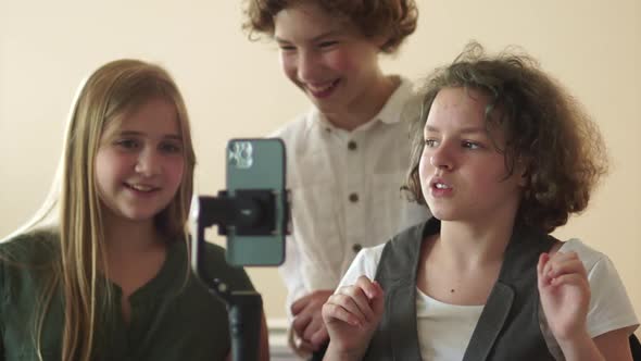 Three Schoolchildren are Filming a Video Using a Smartphone and a Steadicam