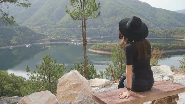 Woman Sitting on a Bench Watches the Lake.