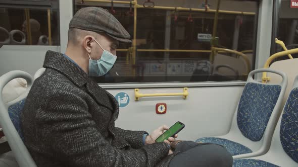 Man is Riding Bus and Looking on Screen of Smartphone