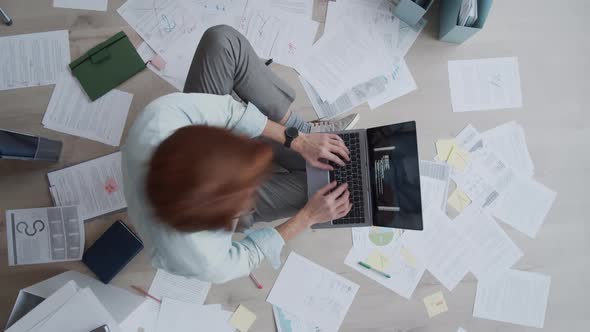 Timelapse of Man Sitting on Floor, Typing on Laptop and Working with Papers