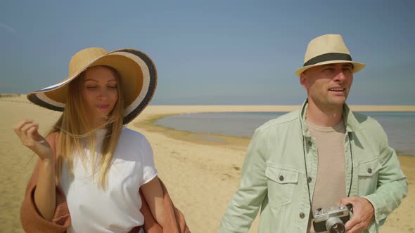 Man Photographing Girlfriend on Sandy Beach