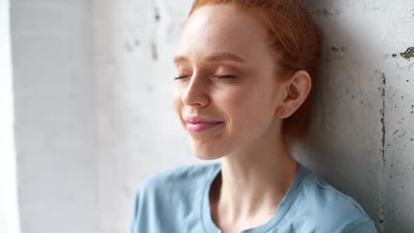 Close-up of Face of Happy Redhead Young Woman with Emotion of Joy and Success Sitting Near Window