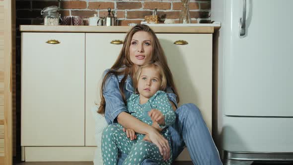 Happy Mothers Day. Hugging mom and daughter dreaming sitting on the floor.