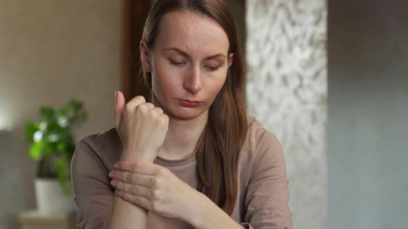 An Unhappy Young Woman Suffering From Wrist Pain at Home