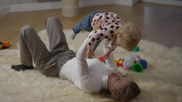 High Angle View of Charming Slim Gorgeous Millennial Mother Talking to Baby Girl Holding Child Up in