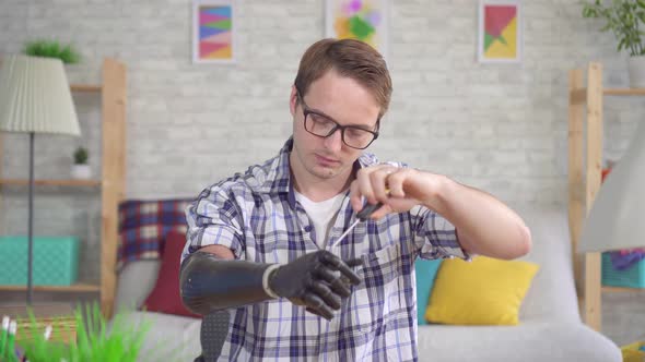 Young Man Adjusts a Bionic Prosthetic Hand with a Screwdriver