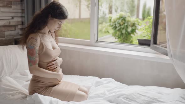 Pretty Expectant Mother Sitting in Light Room