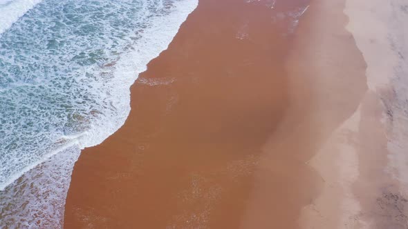 Aerial Drone Shot of Sandy Beach Waves Breaking on Shore, Vertical Top Down View of Golden Sand and