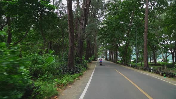 Driving on a street in Phuket, Thailand with a moped on a beautiful avenue