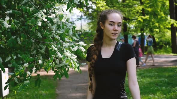 Beautiful Young Girl with a Long Braid Walks in the Park, Go Straight at the Camera, Slow Motion