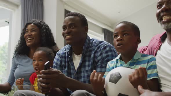 Happy african american family cheering while watching match in tv