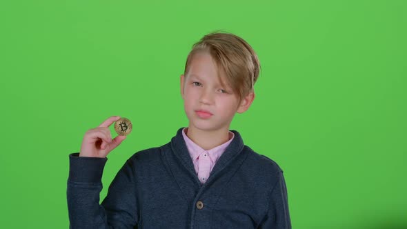 Child Boy Raises His Hand and Shows the Bitcoin on a Green Screen