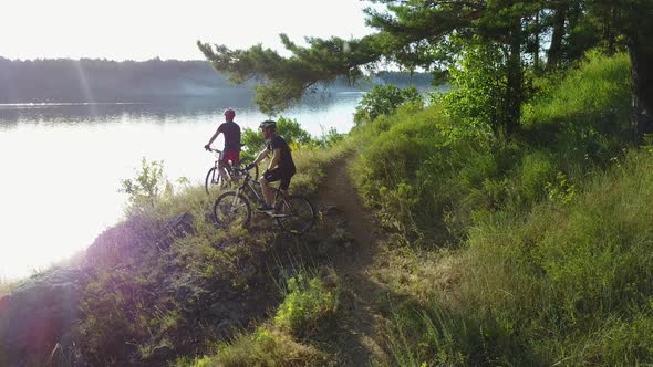 Men Riding Bicycle In Nature. Young male men in sportswear riding bicycle near forest