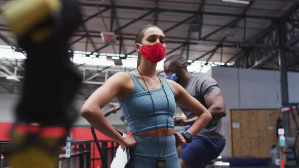 Mixed race female fitness trainer wearing face mask at gym