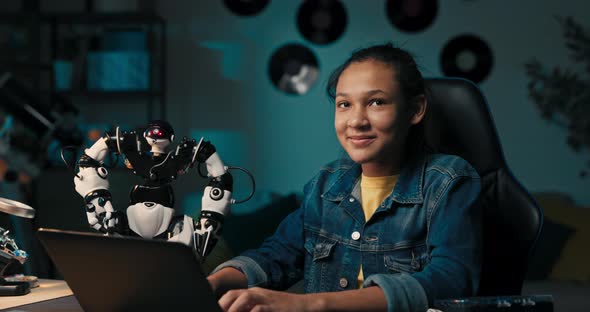 Cheerful Intelligent Student Sitting at Desk at Home Constructing Robotic Device in Spare Time Child