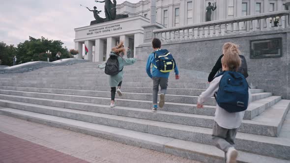 Schoolchildren with Backpacks Running Up Stairs Near School