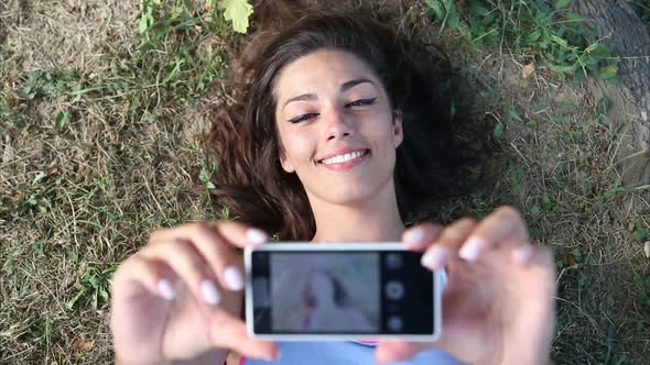 Three young adults taking a selfie lying on the grass