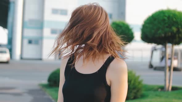 Beautiful Redhaired Woman with Long Hair on Street at Sunset