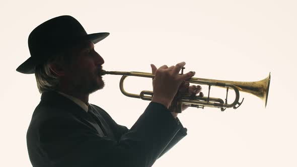 Silhouette of Male Musician in Hat Playing Musical Trumpet Pressing Keys with Fingers on White