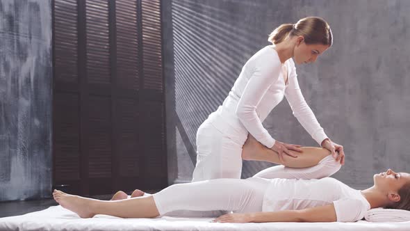 Young woman is getting Thai massage treatment by professional therapist.