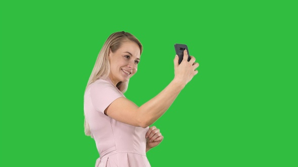 Beautiful young woman doing selfies on a Green Screen, Chroma Key.