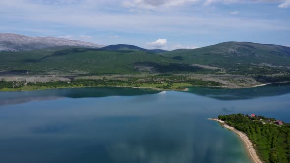 A lake in northern Croatia surrounded by greenery and mountains on a bright partly cloudy day. This