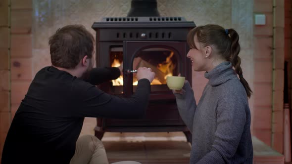 Beautiful Girl Drinks Cup of Tea, Man Puts Firewood in Fireplace Couple Resting