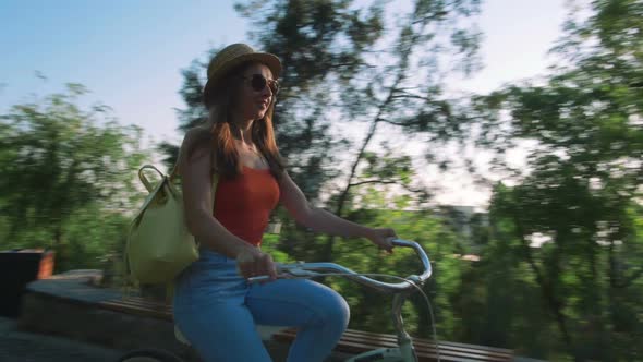 Young Beautiful Woman Riding a Bicycle in a Park