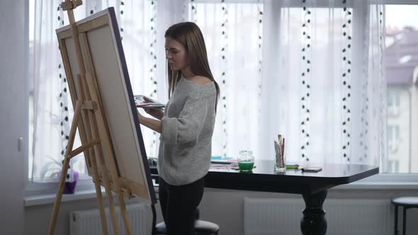 Portrait of Talented Woman Making Strokes on Easel Canvas Painting Picture Indoors