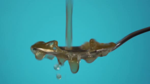 Pouring fresh apple cider vinegar into a metal measuring spoon in slow motion