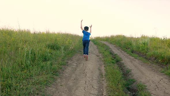 Happy carefree child 6-8 years old runs along a rural road on a summer day