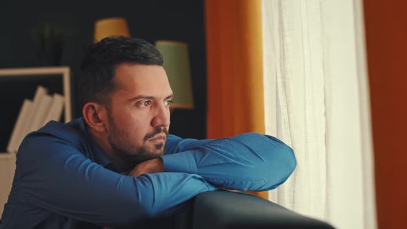 Sad Man Sitting on Windowsill