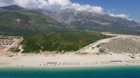 Beach with people relaxing near mountains in Albania