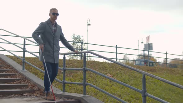 Blind Young Man Descending Stairs Outdoors Using Cane