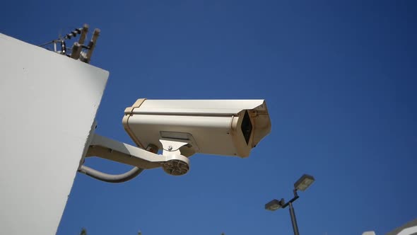 Close-Up White Surveillance Camera With Blue Sky in Background