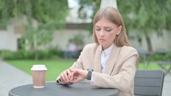 Young Businesswoman with Coffee Waiting Checking Time in Outdoor Cafe