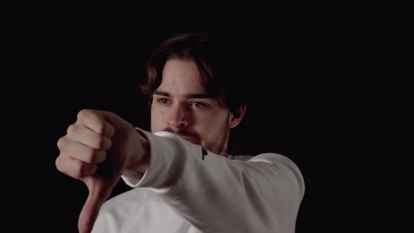 Trendy Young Man giving thumb down, disapproving gestures, close, black background