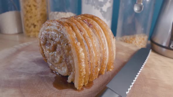 Slider Shot of Breaking a Roast Pork Belly Joint on a Cutting Board in the Kitchen