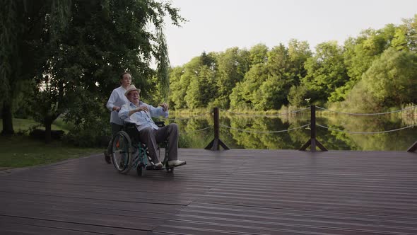 Nurse and Old Patient Walk Near the Park Lake