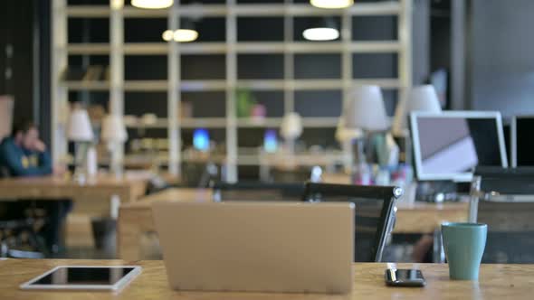 Young Male Designer Coming and Sitting in Modern Office