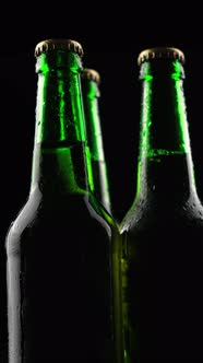 Three Green Glass Beer Bottles Spinning on a Black Background in the Dark
