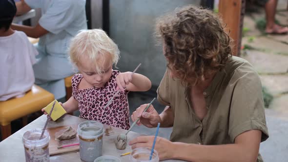 Cute Blonde Toddler Learning Pottery on Art Workshop with Young Mother Enjoying Family Time Together