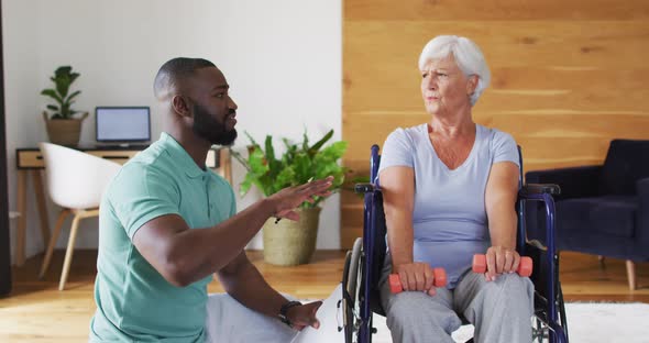 Video of african american male physiotherapist exercising with caucasian senior woman