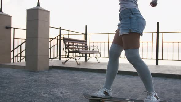 Young Stylish Attractive Woman Skateboarding at Sunrise on Seafront Slow Motion Close Up
