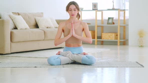 Young woman doing yoga with closed eyes at home