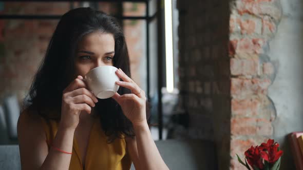 Cheerful Girl Drinking Tea in Cafe Holding Cup and Smiling Enjoying Drink