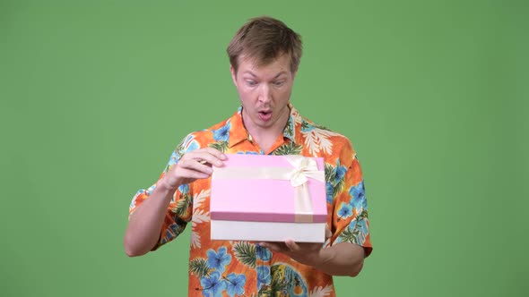 Young Handsome Tourist Man Opening Gift Box and Looking Surprised