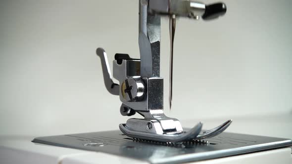 The needle of a sewing machine makes a thread stitch. Slow motion.