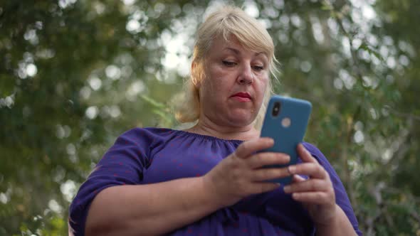 Fat Woman Uses Smartphone at the City