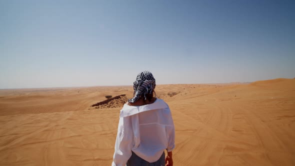 Young Caucasian Woman with Scarf and Sunglasses Walking Around Sand Dunes in the Desert